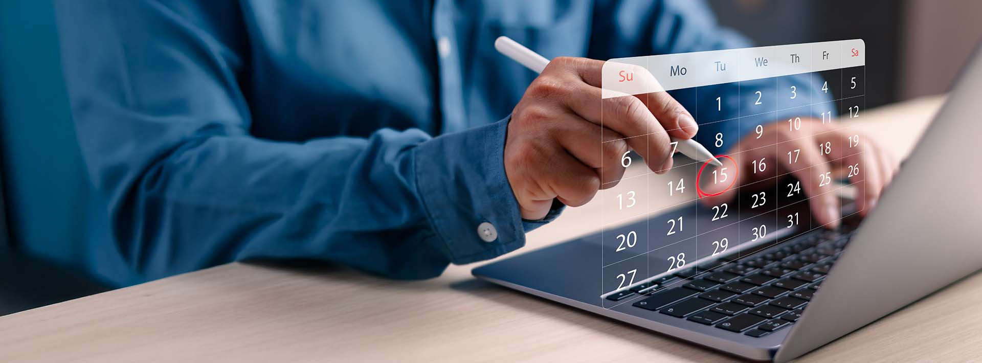 Dłonie korzystające z laptopa z widocznym kalendarzem i zaznaczonymi datami spłat rat kredytu