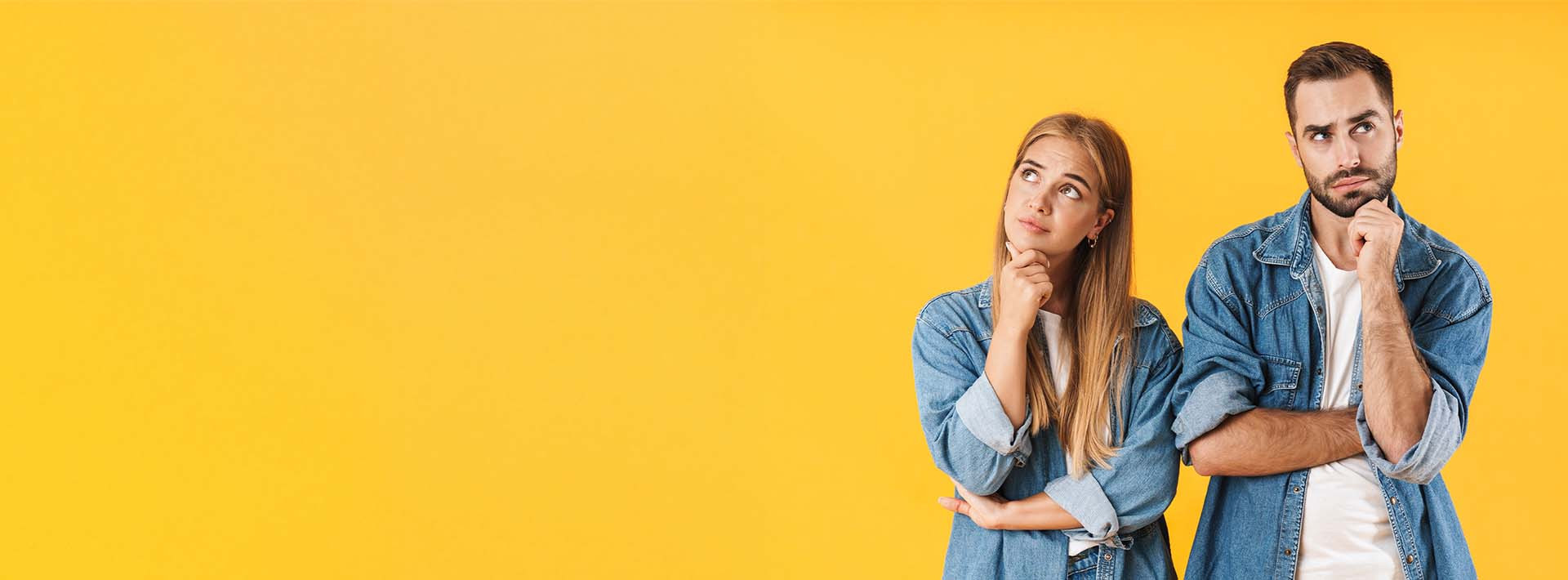 Kobieta i mężczyzna w dżinsowych koszulach wykonujący gest zadumy, patrzą w górę, co sugeruje zastanawianie się i niepewność