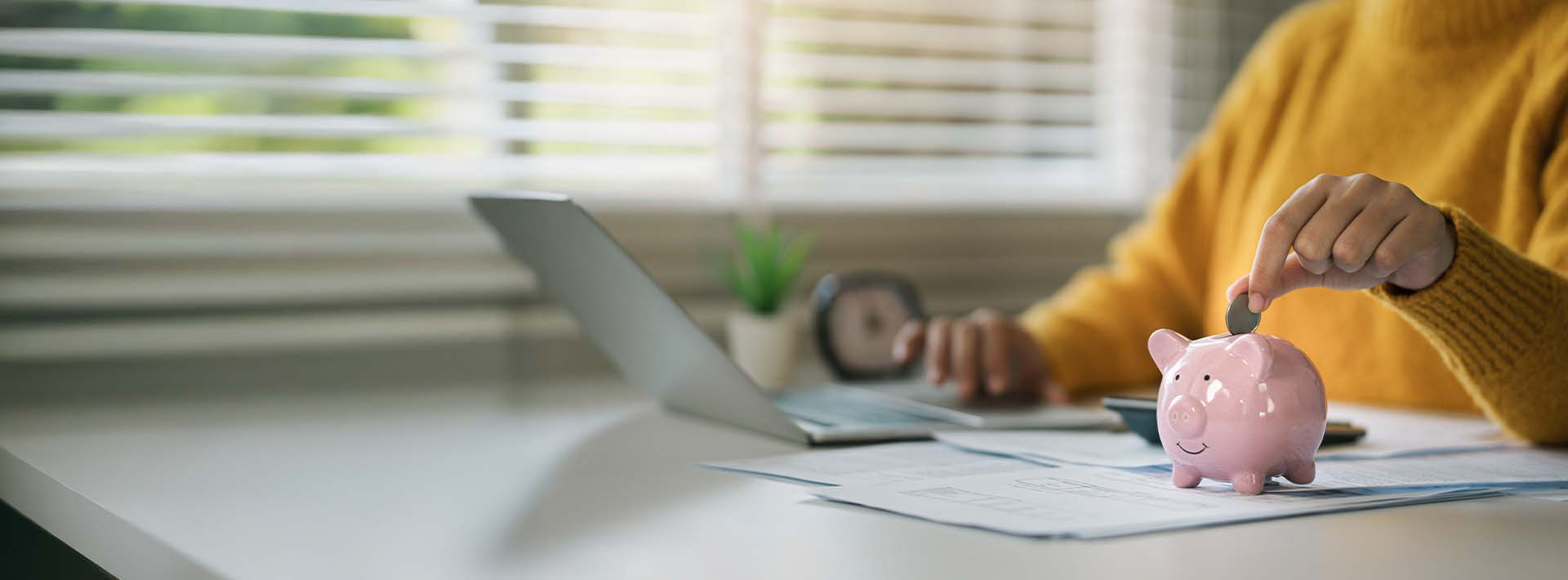 Odkładanie pieniędzy do skarbonki na biurku