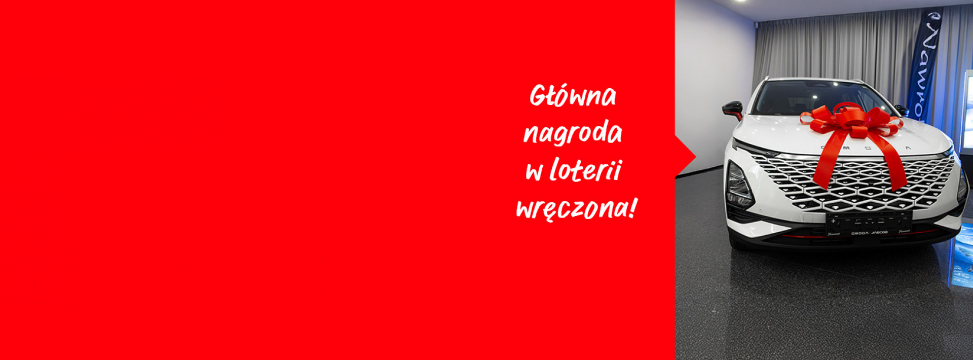 widzimy auto z czerwoną kokardą i napis Główna nagroda w loterii wręczona!