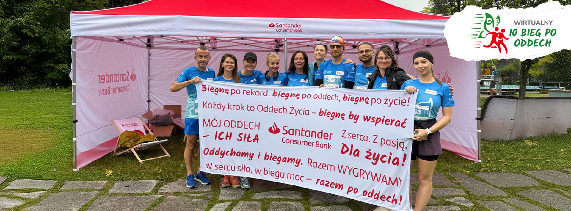 Grupa biegaczy, pracowników banku z transparentem promującym bieganie w szczytnych celu