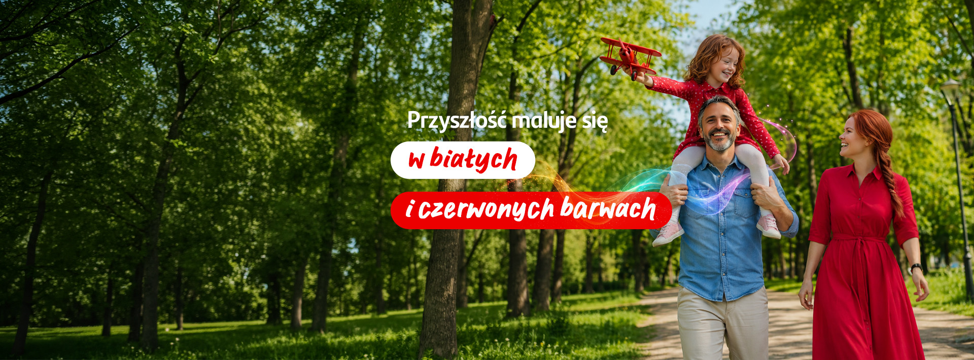 Rodzina spacerująca w parku; dziewczynka trzyma biało-czerwony samolot, na banerze hasło: "Przyszłość maluje się w białych i czerwonych barwach"