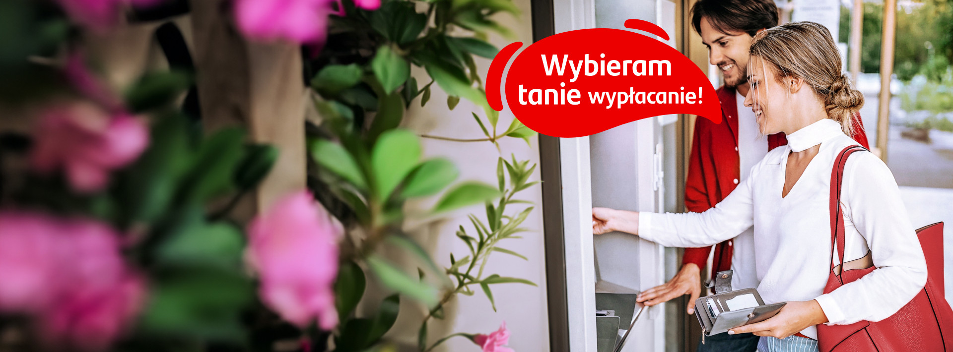 kobieta obok bankomatu mówi: wybieram tanie wypłacanie