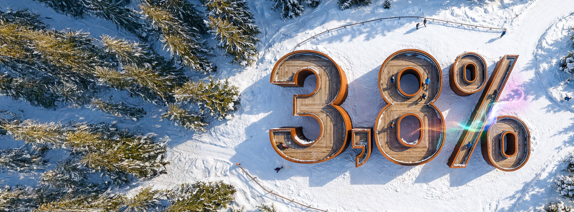 Widok z lotu ptaka na leśną polanę w śniegu, na niej budynek w kształcie liczby 3,8% symbolizująca oprocentowanie lokaty