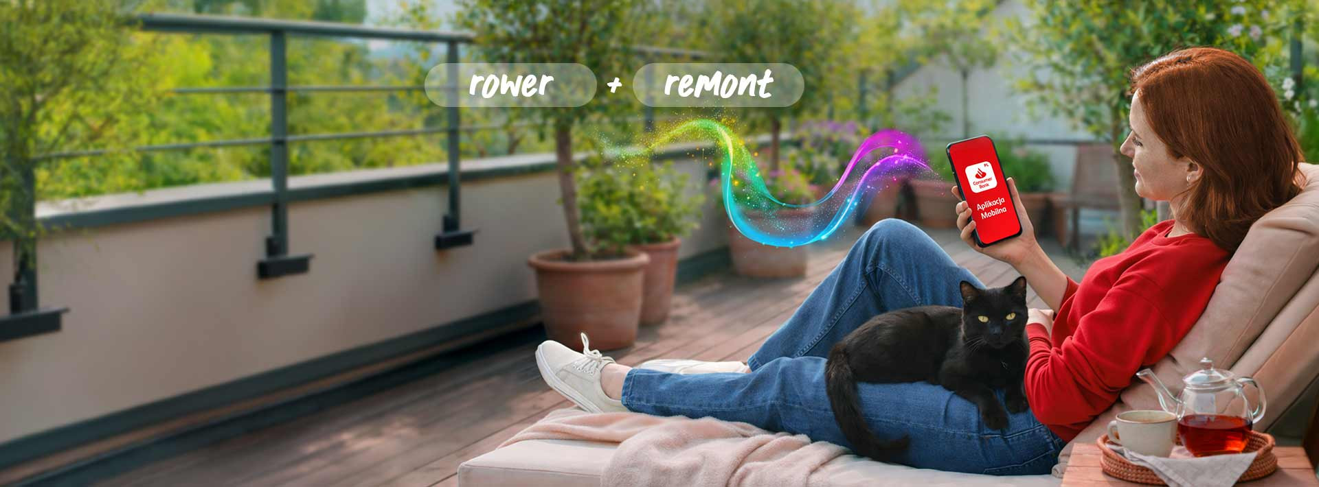 Kobieta siedząca na balkonie z kotem na kolanach i przeglądająca aplikację Santander Consumer Bank na telefonie. Na górze baneru napis rower+remont.