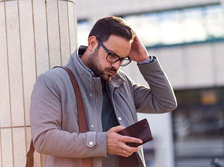 Zestresowany mężczyzna patrzy na telefon, trzymając rękę na czole.