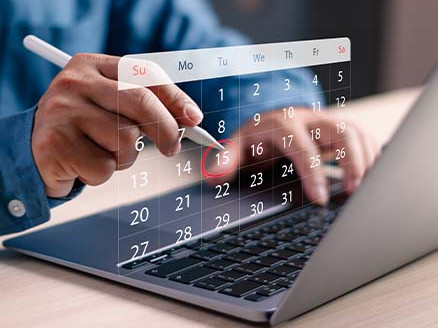 Dłonie korzystające z laptopa z widocznym kalendarzem i zaznaczonymi datami spłat rat kredytu