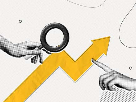 Dłoń trzymająca lupę nad rosnącym wykresem strzałkowym