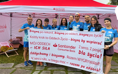 Grupa biegaczy, pracowników banku z transparentem promującym bieganie w szczytnych celu