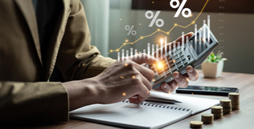 Osoba pracująca przy laptopie, widoczny wykres wzrostu i symbole procentowe