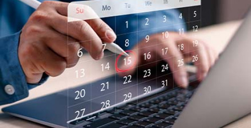 Dłonie korzystające z laptopa z widocznym kalendarzem i zaznaczonymi datami spłat rat kredytu