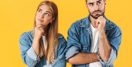 Kobieta i mężczyzna w dżinsowych koszulach wykonujący gest zadumy, patrzą w górę, co sugeruje zastanawianie się i niepewność