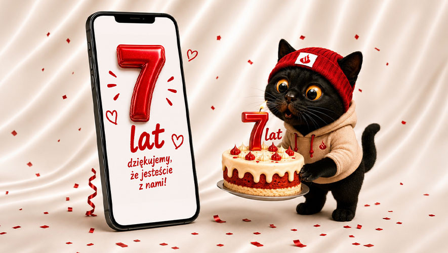 Czarny kot w czerwonej czapce trzyma urodzinowy tort. Obok telefon z napisem: 7 lat, dziękujemy, że jesteście z nami!